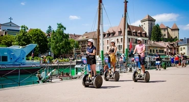 Une guide et ses deux clients à Segway qui se déplacent au bord du lac sous le soleil.
